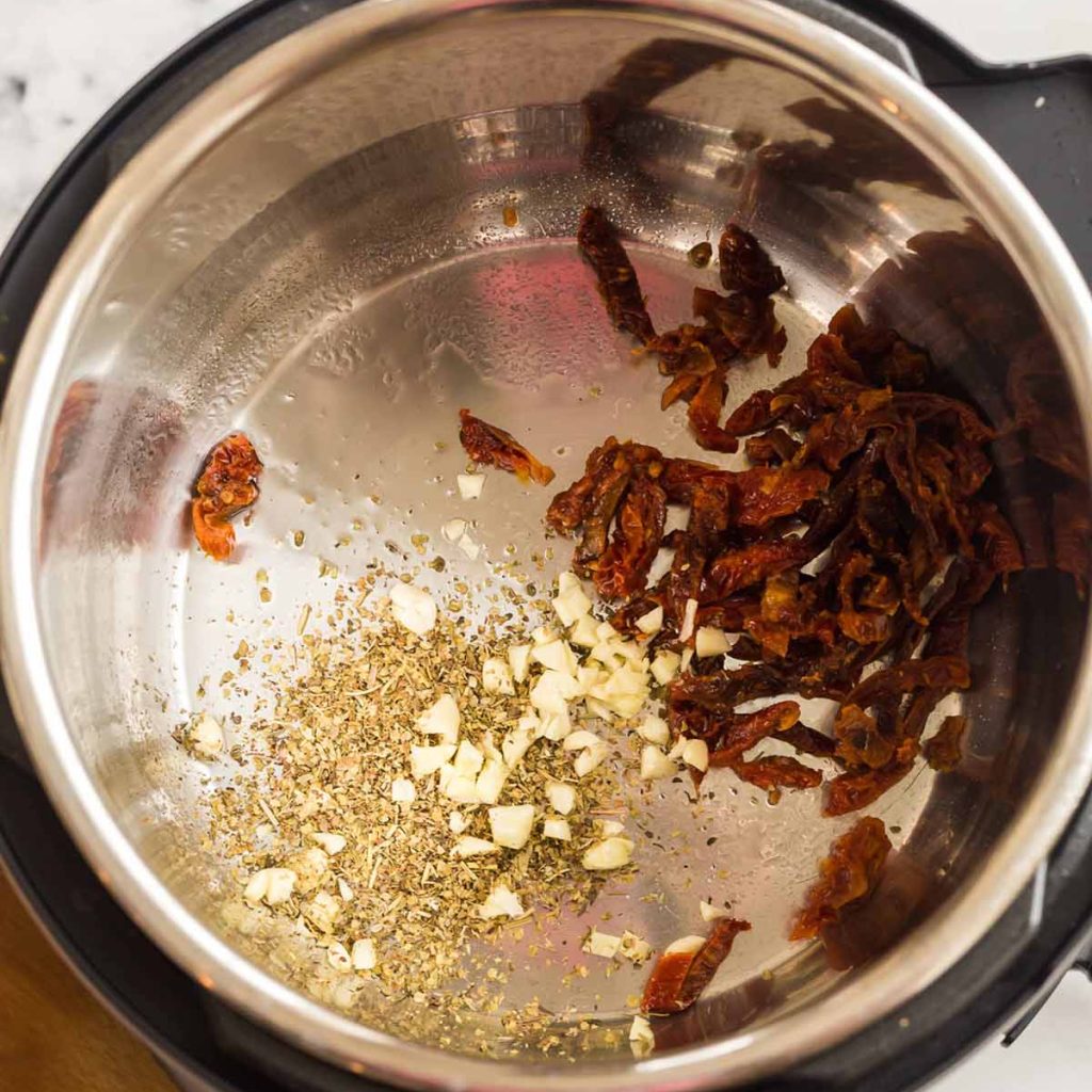 top down view of ingredients in an Instant Pot while making Tuscan Chicken Pasta