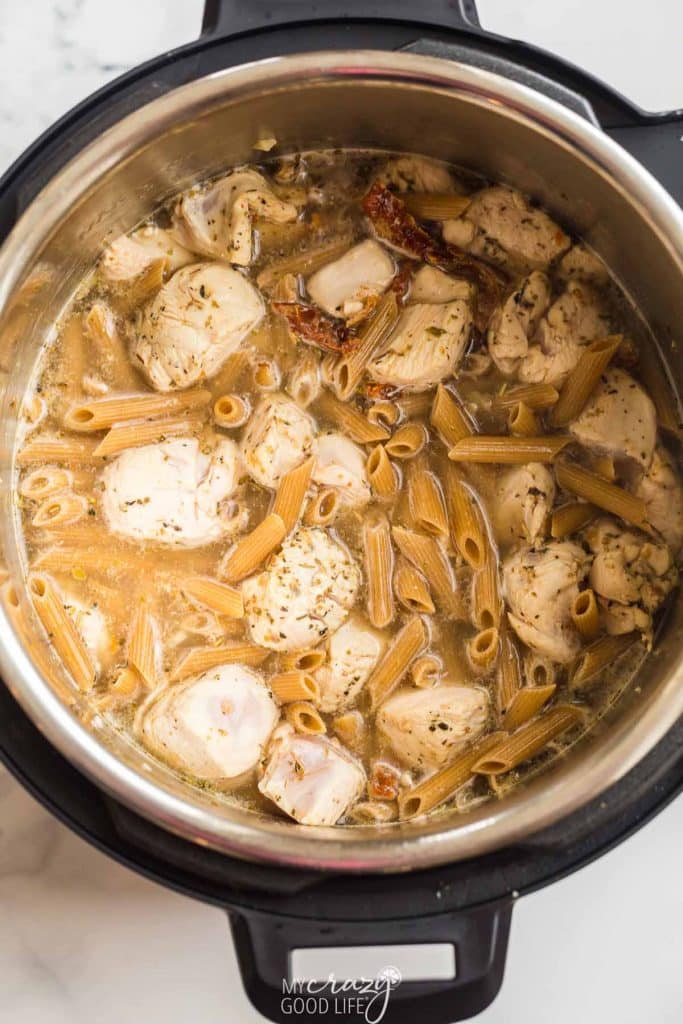 top down view of cooked ingredients in the Instant pot - chicken, pasta, broth, spices. 