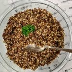 Glass bowl full of cooked red quinoa and brown rice, topped with parsley.