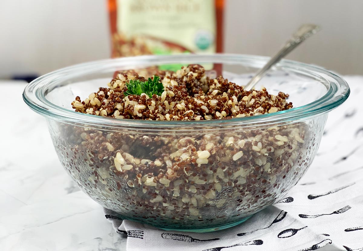 Clear bowl of cooked Quinoa and Brown Rice with a sprig of parsley on top. 