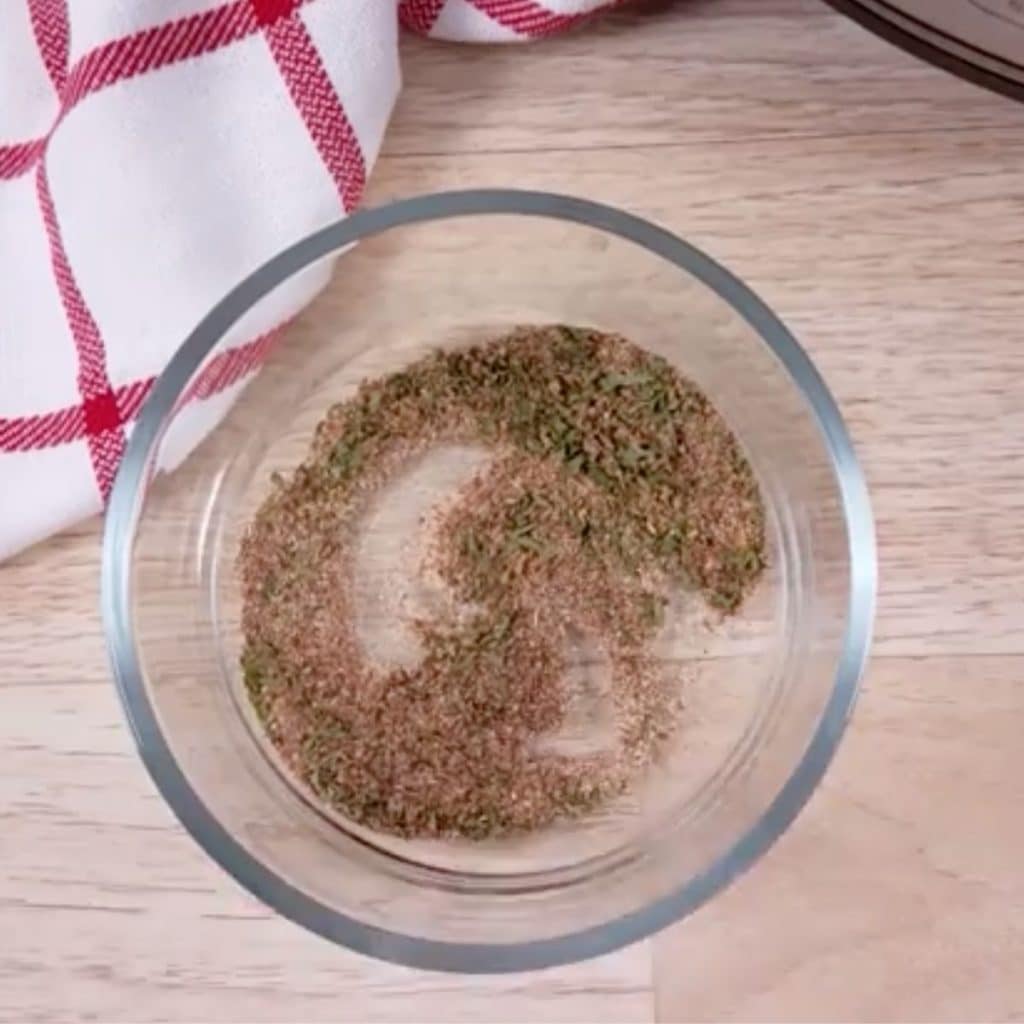 A small glass bowl with seasonings that have been mixed together.