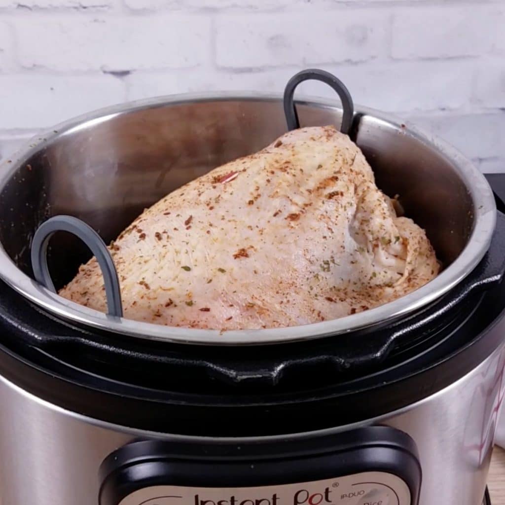 A raw turkey breast sitting on a trivet inside an Instant Pot about to be cooked.