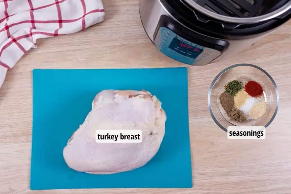 A blue cutting board with a raw turkey breast on top of it, and off to the side is a bowl with seasonings.