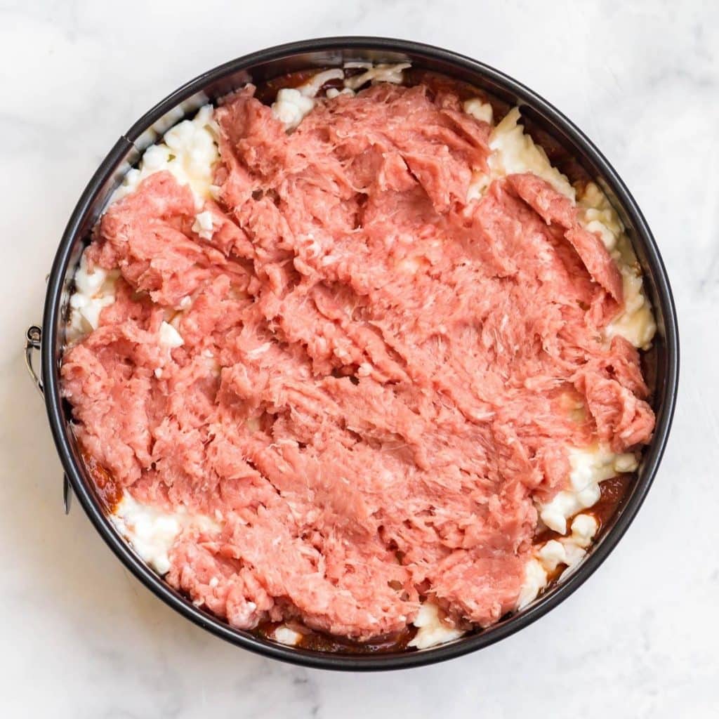 A circular Instant Pot pan with layers of lasagna, showing the current layer of ground turkey right on top of the ricotta and mozzarella mixture.