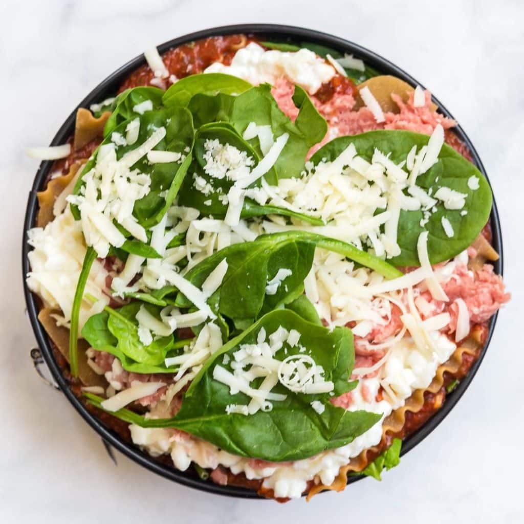 A circular Instant Pot dish with layers of healthy lasagna showing the top layers being spinach and cheese.