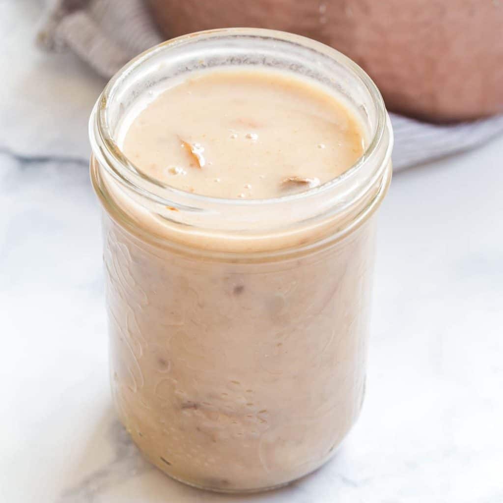 A glass mason jar without a lid filled with cream of mushroom soup.