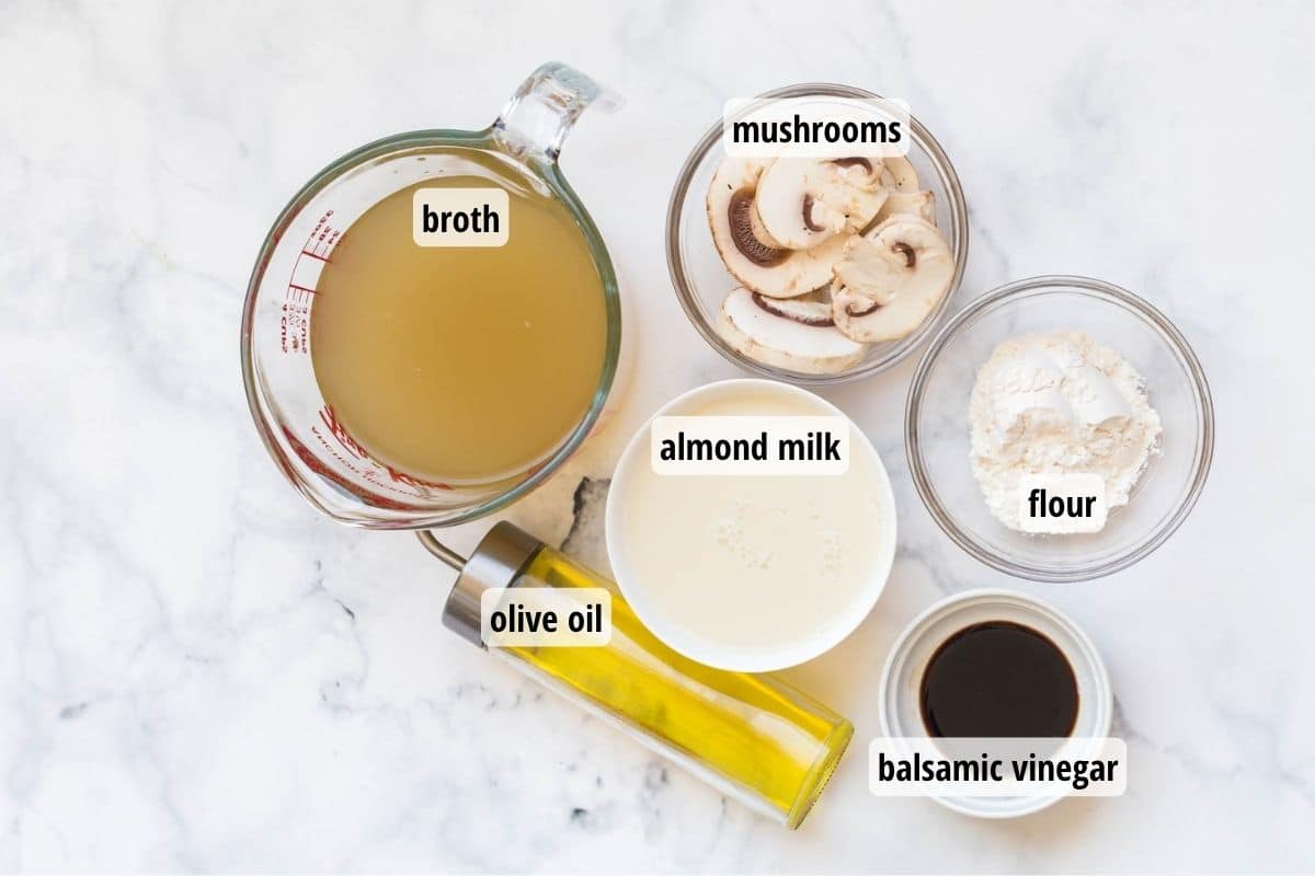 A white marbled counter top with bowls of labeled ingredients needed to make cream of mushroom soup.