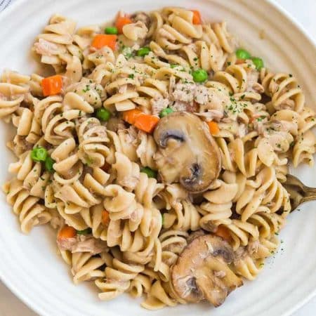 White bowl with tuna casserole in it. There is a fork sticking out of the side of the bowl.