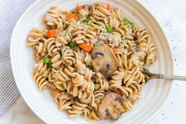 White bowl with tuna casserole in it. There is a fork sticking out of the side of the bowl.