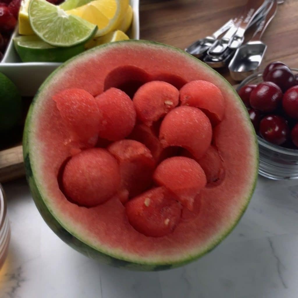 A small watermelon with balls of the fruit scooped out and then placed back inside the rind.