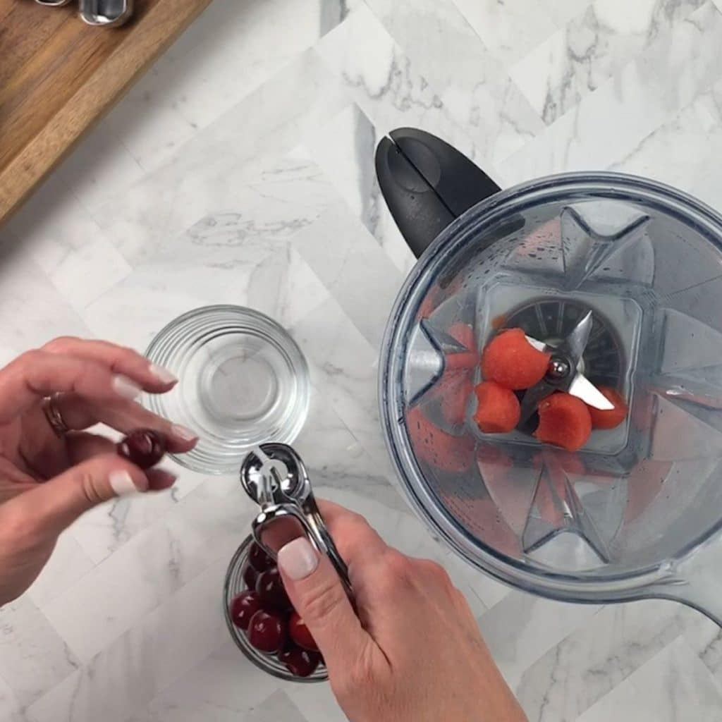 An image of cherries being pitted next to a blender that has several watermelon balls inside.