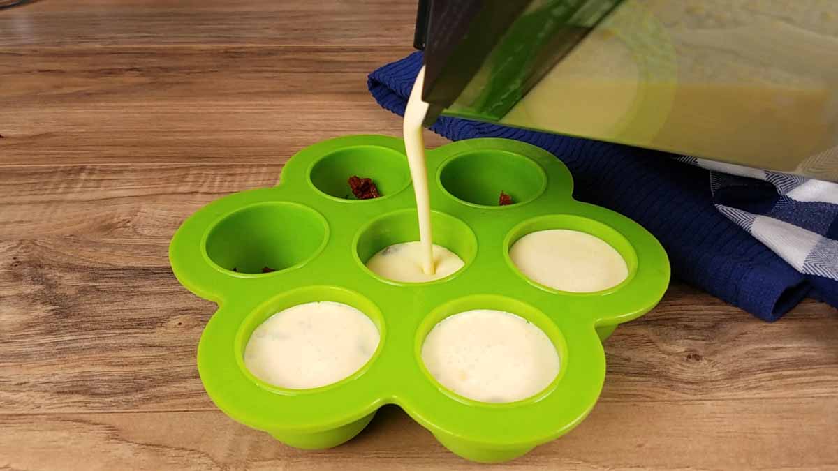 image of egg bite batter being poured into a green silicone egg bite mold.
