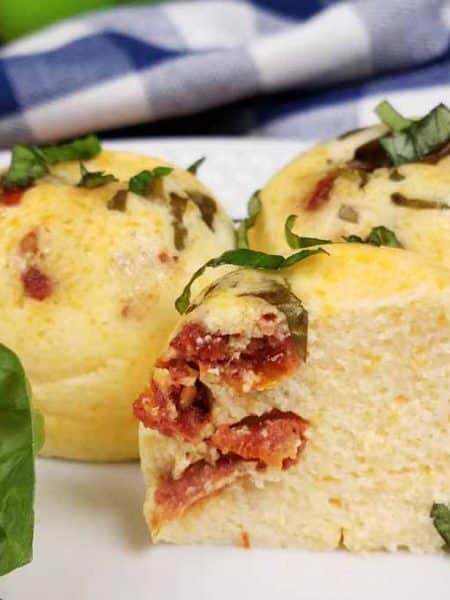image of three egg bites on a white plate with fresh basil as garnish.