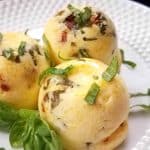 image of three egg bites on a white plate with fresh basil as garnish.
