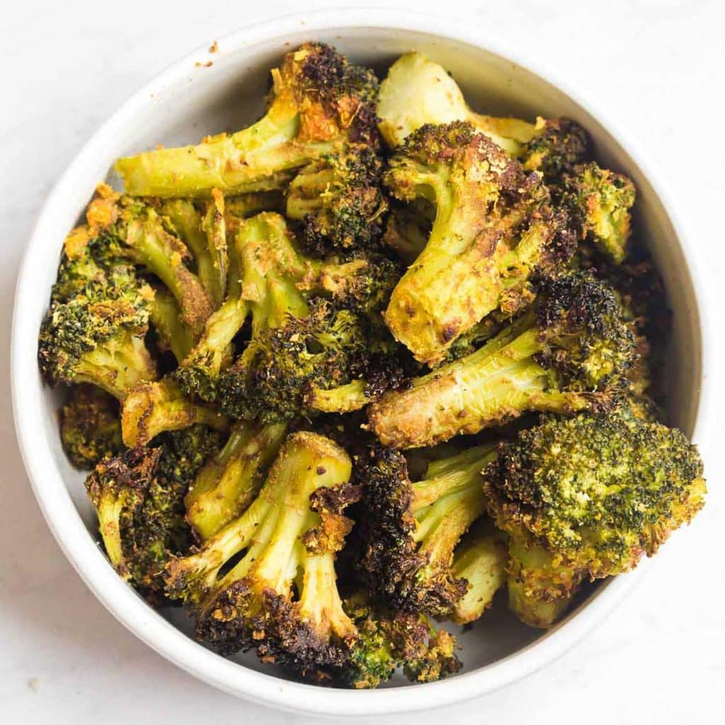 White bowl of cooked and air fried frozen broccoli. 