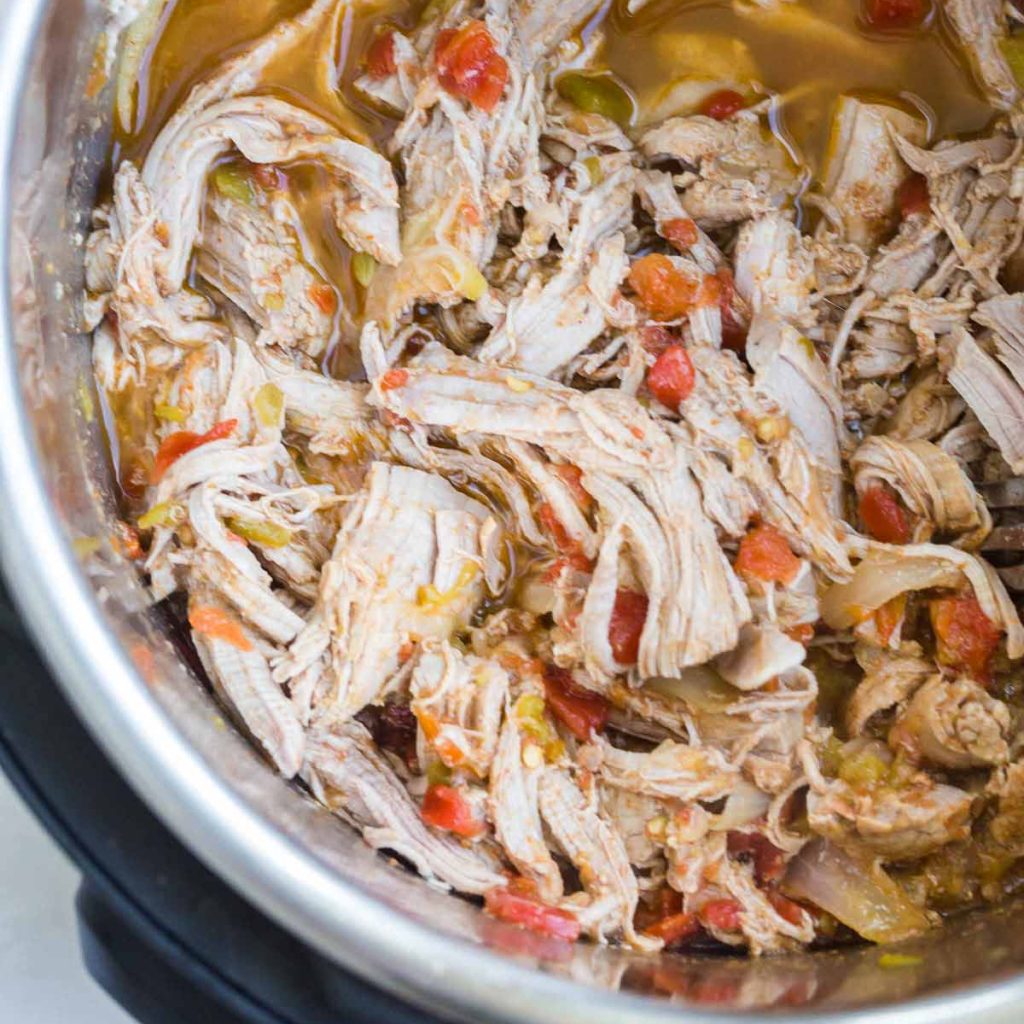 Instant Pot with cooked, shredded, and stirred Pork Carnitas inside.