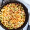 A large cast iron skillet with a baked zucchini breakfast casserole inside of it.
