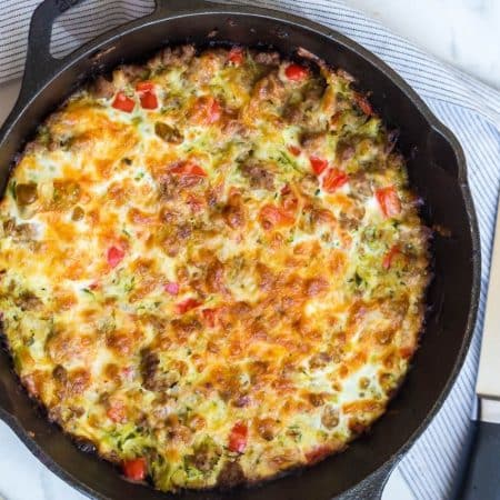 A large cast iron skillet with a baked zucchini breakfast casserole inside of it.