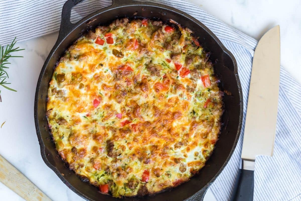 A large cast iron skillet with a baked zucchini breakfast casserole inside of it.