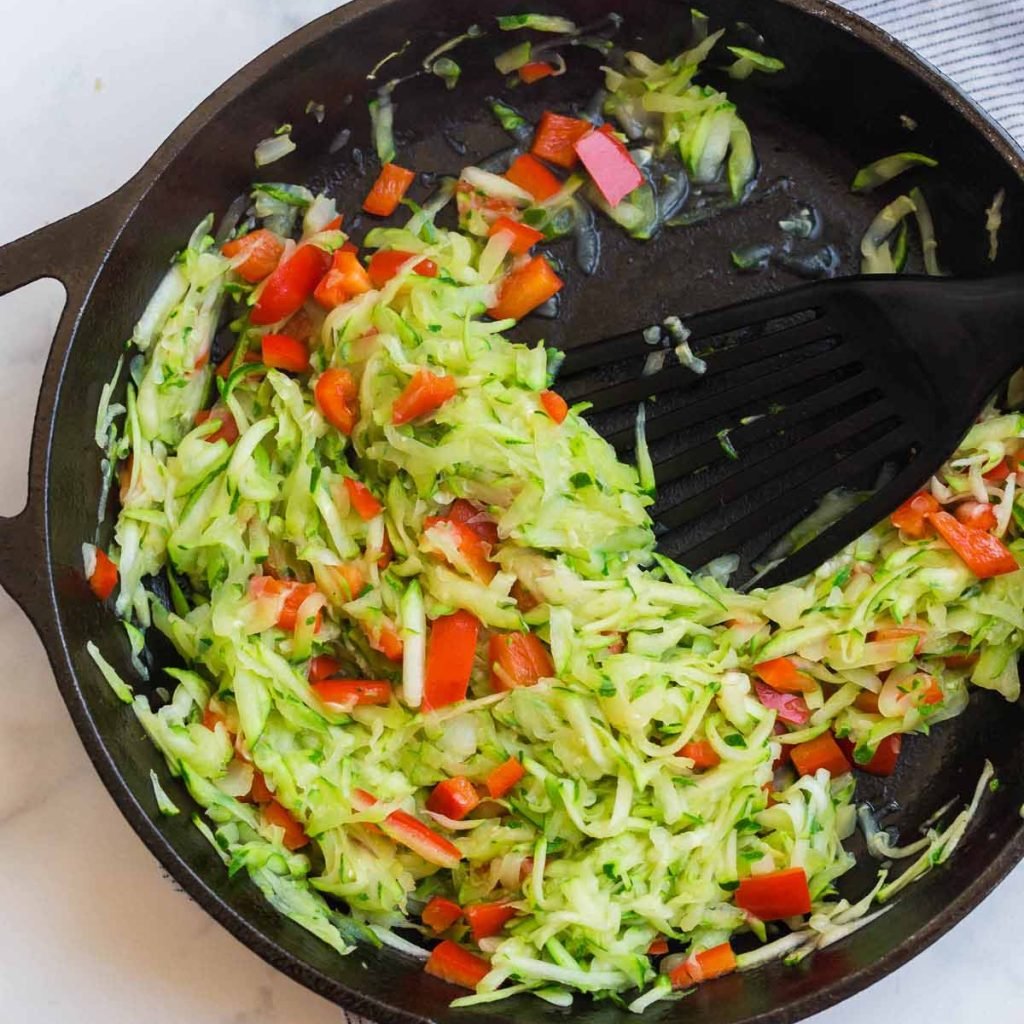 cast iron skillet with shredded zucchini being cooked