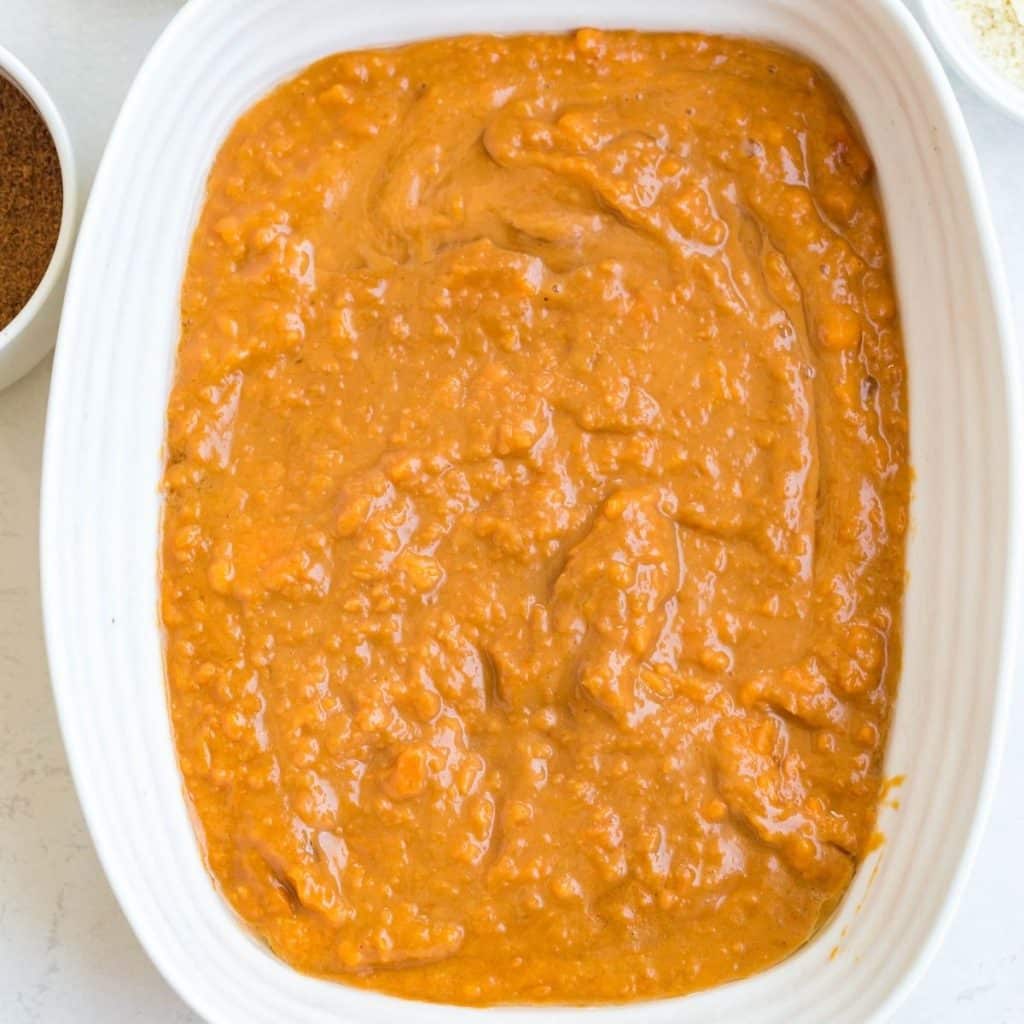 A white rectangular baking dish filled with mashed sweet potatoes.