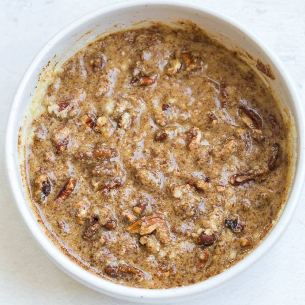 A white bowl filled with a mixture of butter, pecans, almond flour, and coconut sugar.