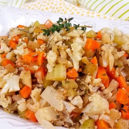 A white platter with cooked cauliflower stuffing with a sprig of thyme on top.