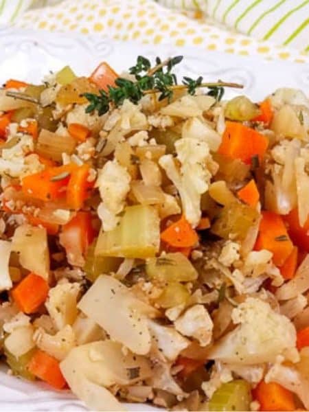 A white platter with cooked cauliflower stuffing with a sprig of thyme on top.