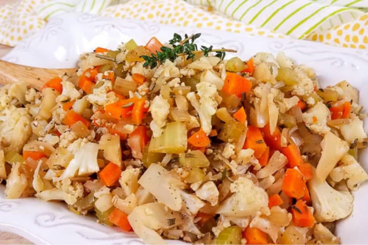 A white platter with cooked cauliflower stuffing with a sprig of thyme on top.