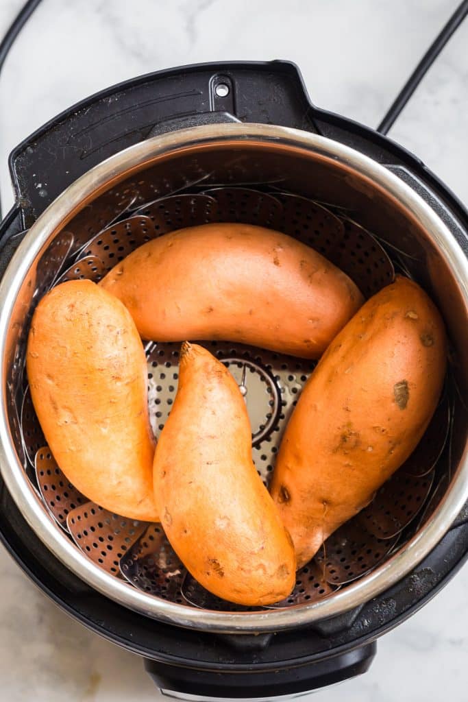 Four sweet potatoes inside an Instant Pot about to be cooked.