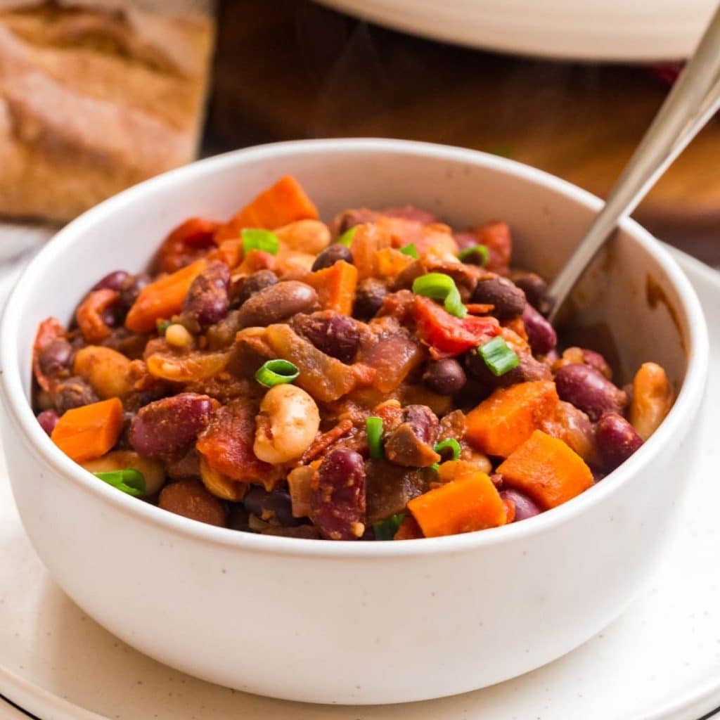 A white bowl with a spoon dipping into vegan chili.