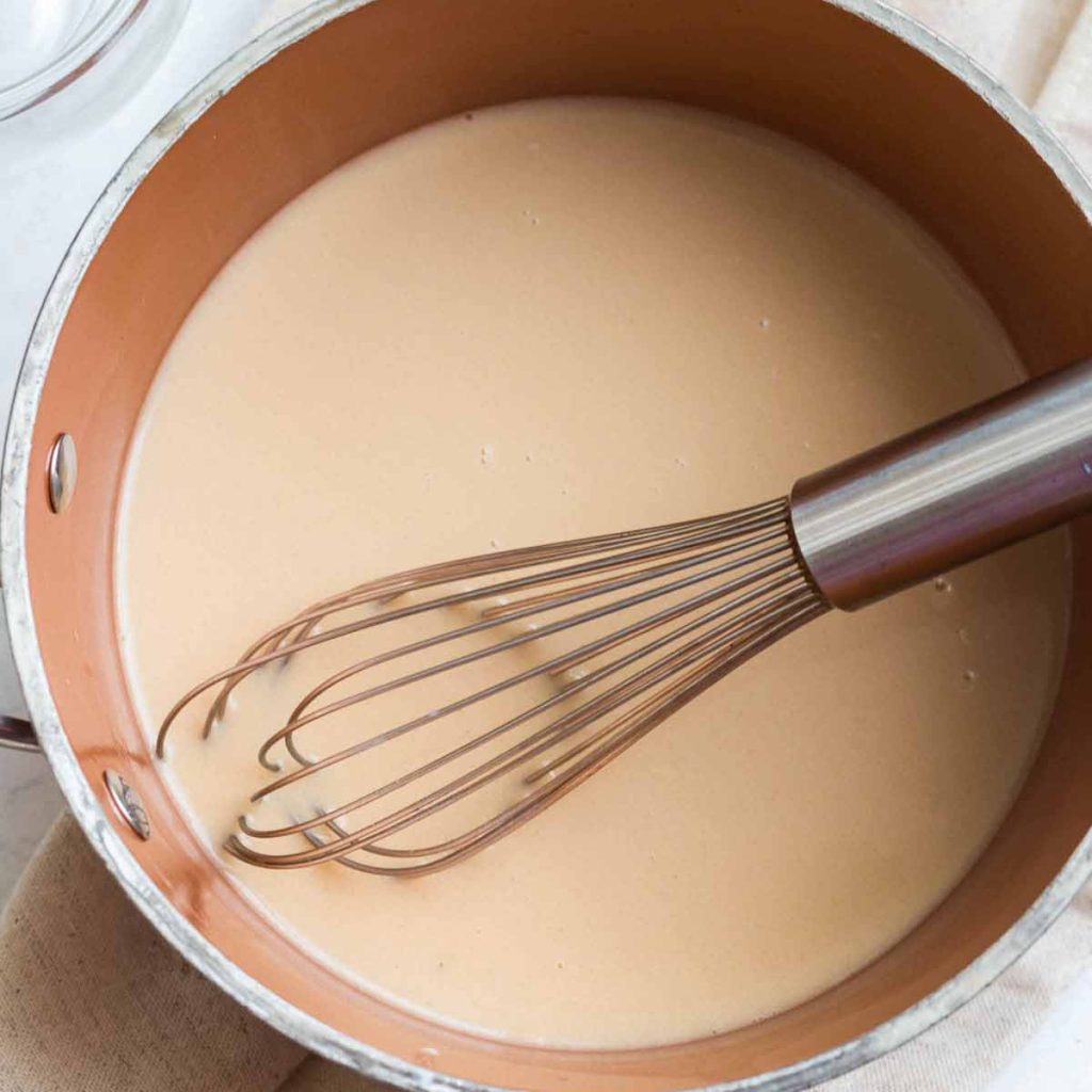 Copper pot on a countertop that contains all of the ingredients for this homemade coffee creamer recipe, heated and mixed together.
