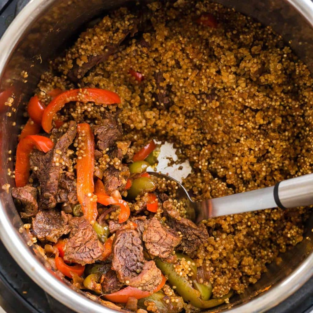 Cooked steak, fajita vegetables and quinoa inside of an instant pot.