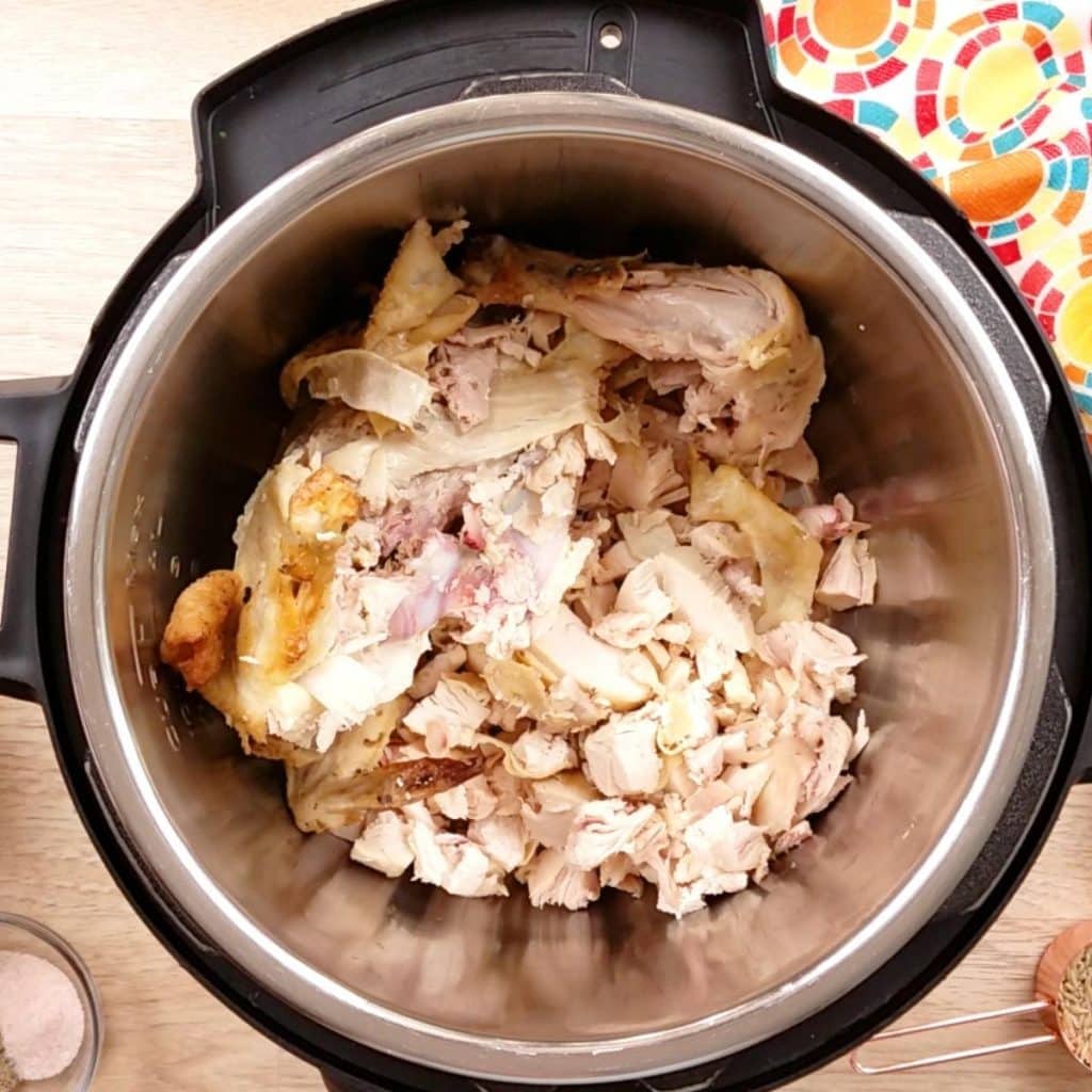 An Instant Pot with chicken bones, meat, and skin inside to make rotisserie chicken soup.