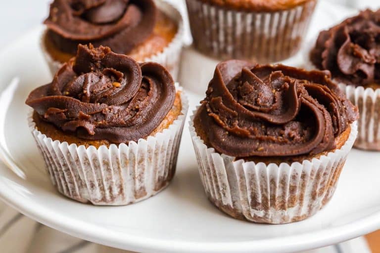 Banana Cupcakes with Chocolate Peanut Butter Frosting in paper liners on top of a white cakestand