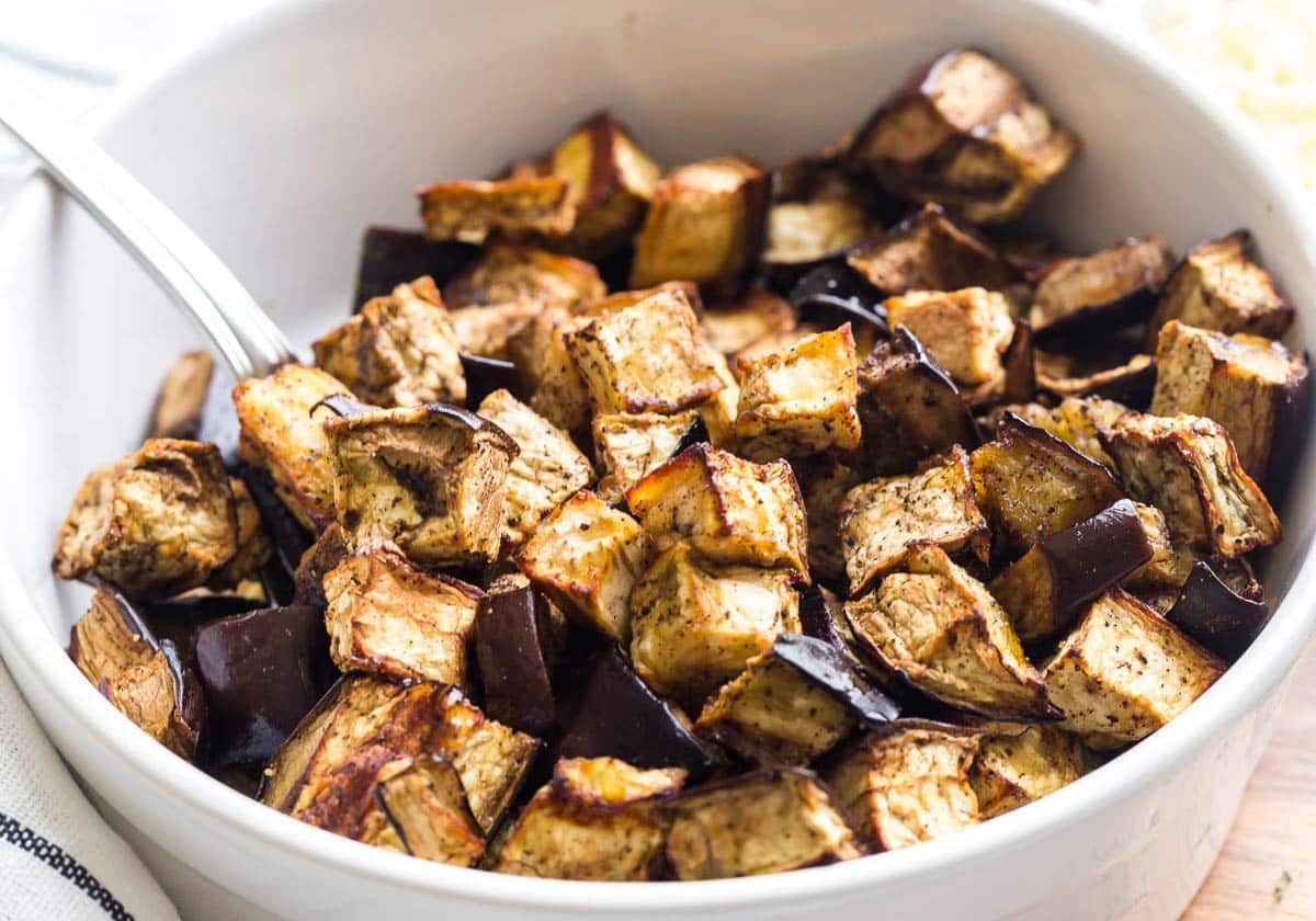 Air fried eggplant cubes in a white bowl.