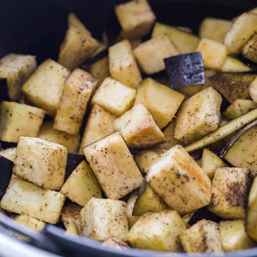 Close up view of cubed and seasoned eggplant inside of an airfryer.