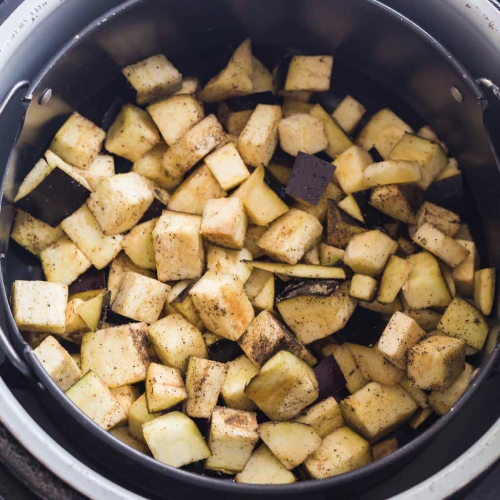 Cubed eggplant inside of an air fryer after half of the cook time.