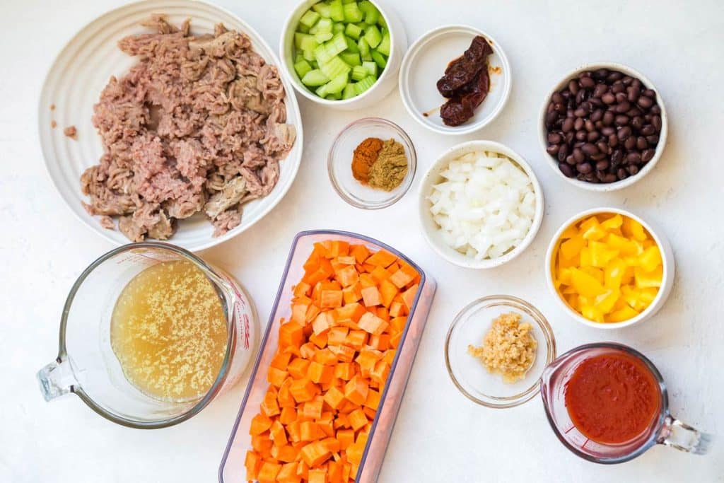 ingredients to make chili including ground turkey, diced sweet potatoes, spices, bell peppers, black beans and chipotle peppers