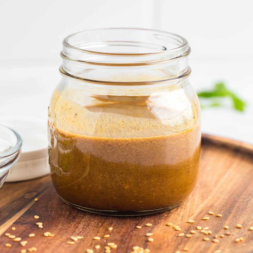 small glass jar of homemade teriyaki sauce on a wood platter