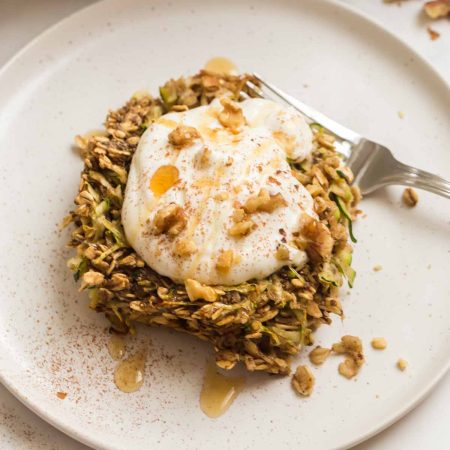 Piece of zucchini bread baked oatmeal with Greek yogurt topping on a white plate.