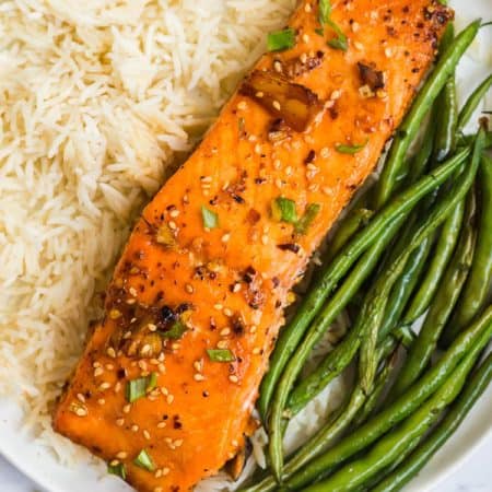 white plate with white rice, grilled salmon, and green beans