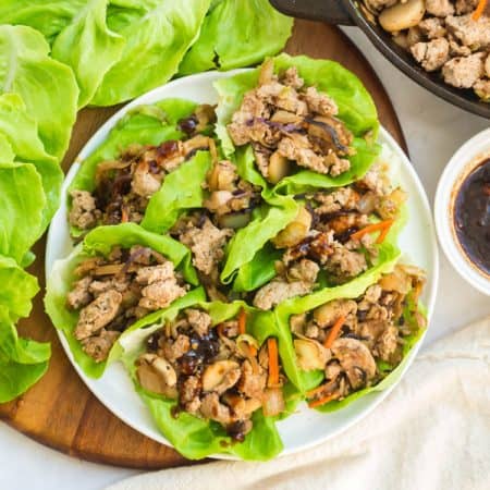 white plate of turkey lettuce wraps with small white bowl of sauce on the right side