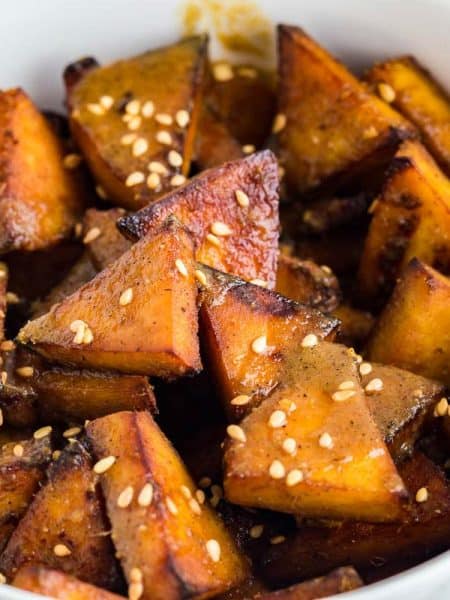 close up of white bowl with triangles of cooked air fryer tofu inside, topped with sesame seeds
