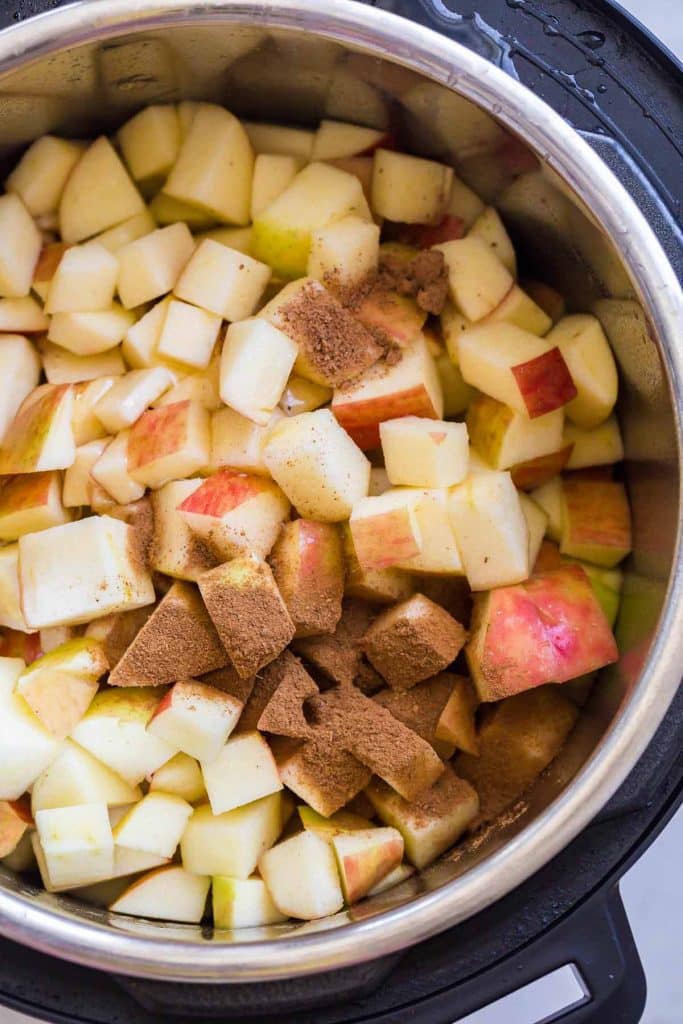 diced apples with cinnamon are inside of an inner pot of an instant pot.