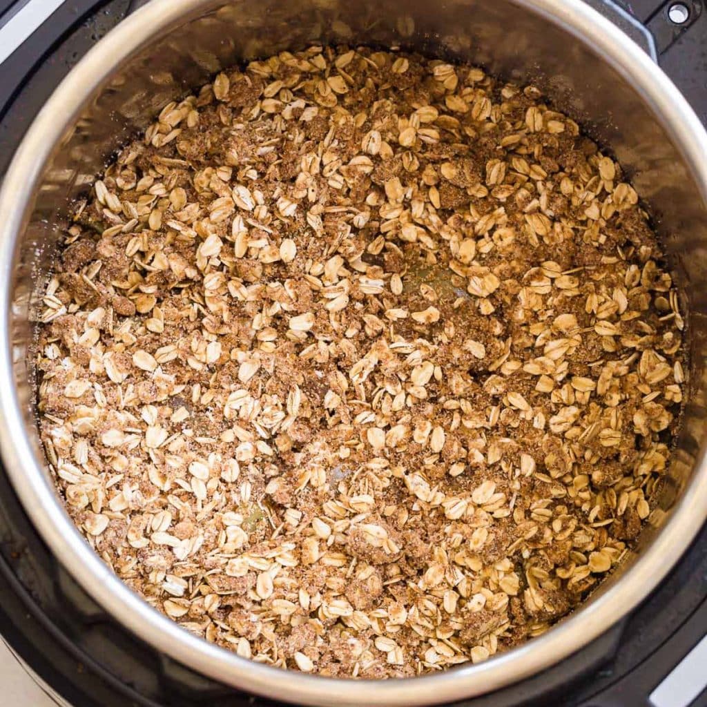 view of inner pot of an instant pot with the oat crumble topping the cooked apples underneath.