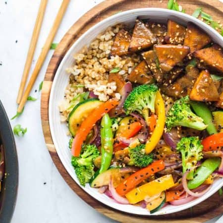 Teriyaki tofu stir fry bowls with coconut rice in a white bowl on a wooden cutting board