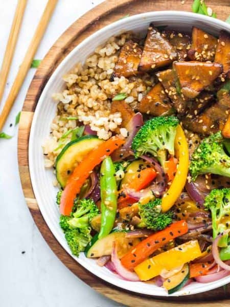 Teriyaki tofu stir fry bowls with coconut rice in a white bowl on a wooden cutting board