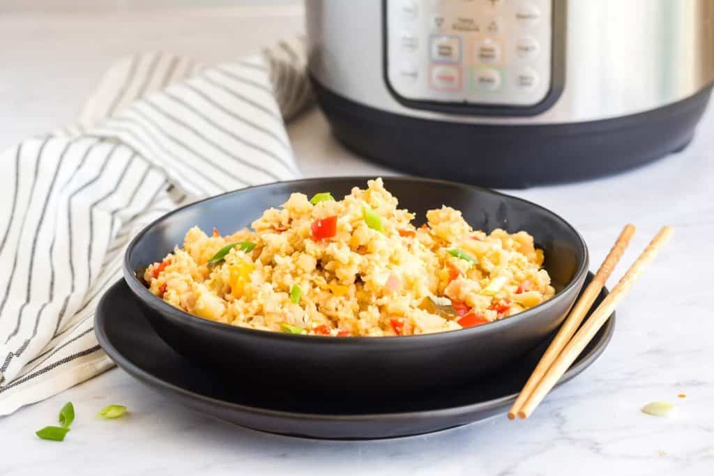 black bowl of Healthy Cauliflower Fried Rice with instant pot in background