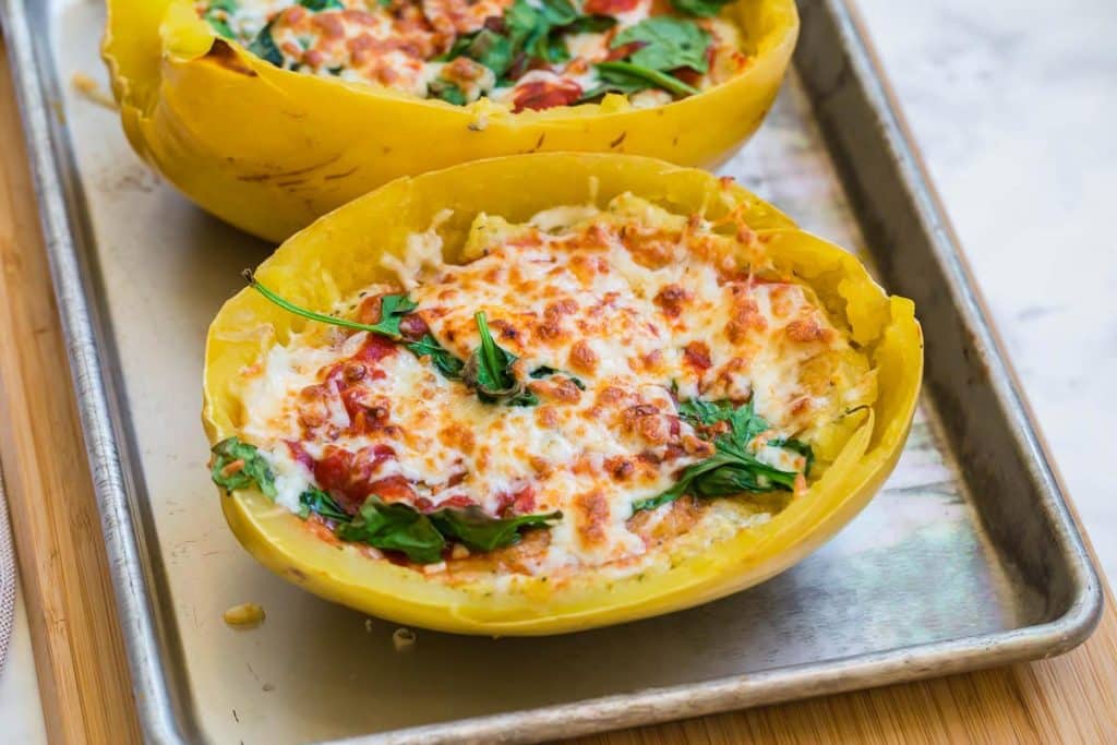 lasagna in a spaghetti squash with spinach and melted cheese on a baking sheet